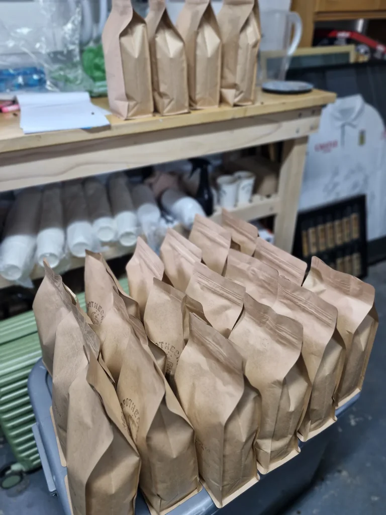 Rows of filled kraft Apothecary coffee bags packed and lined up on a table in the roastery, ready to be sealed and shipped.