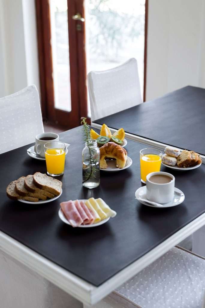 Guest house breakfast table set with coffee, juice, bread and pastries