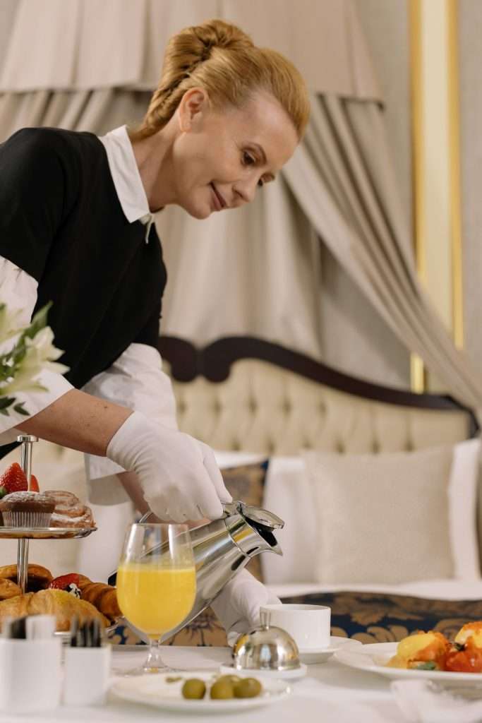 Hotel staff serving a breakfast tray with coffee and juice in a guest room