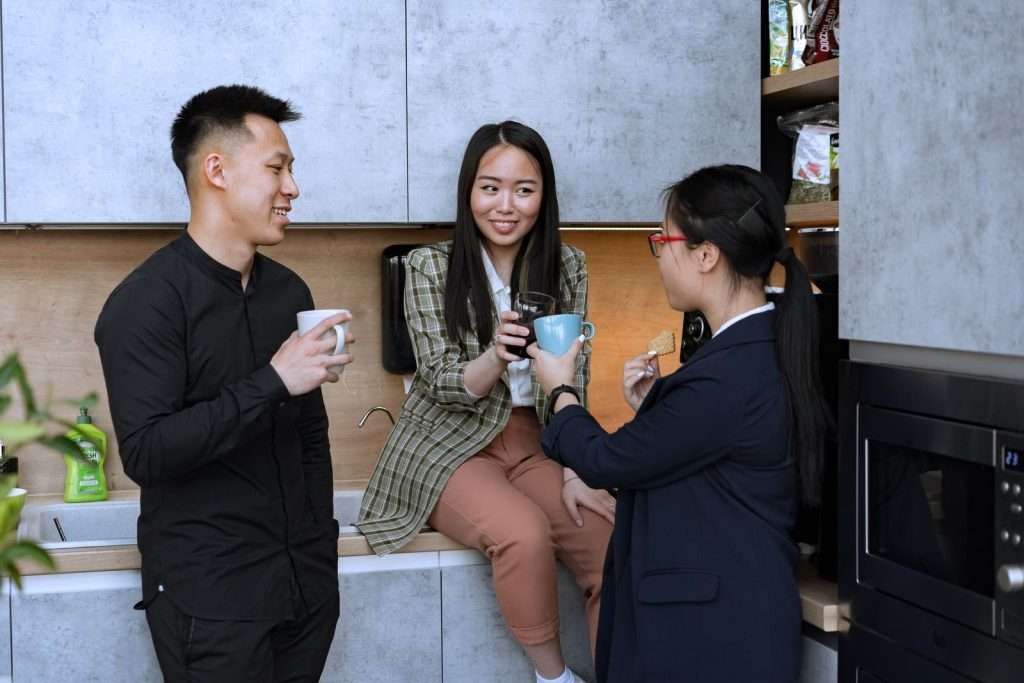 Colleagues chatting over mugs of coffee in a modern office kitchen