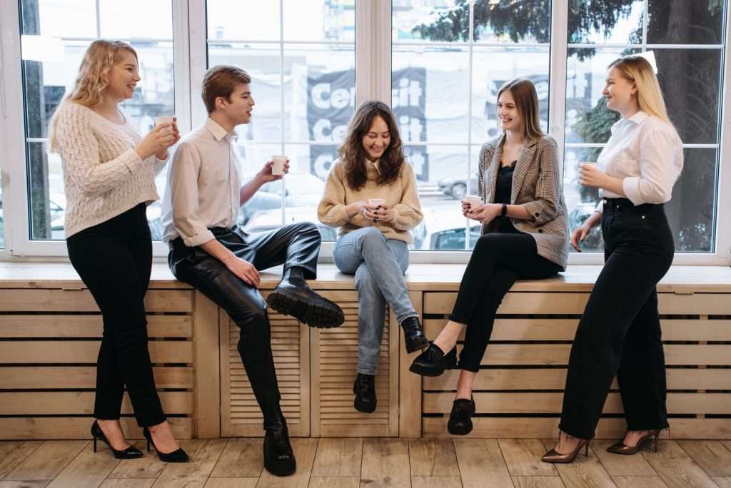 Office colleagues taking a coffee break together by the window in a bright workspace