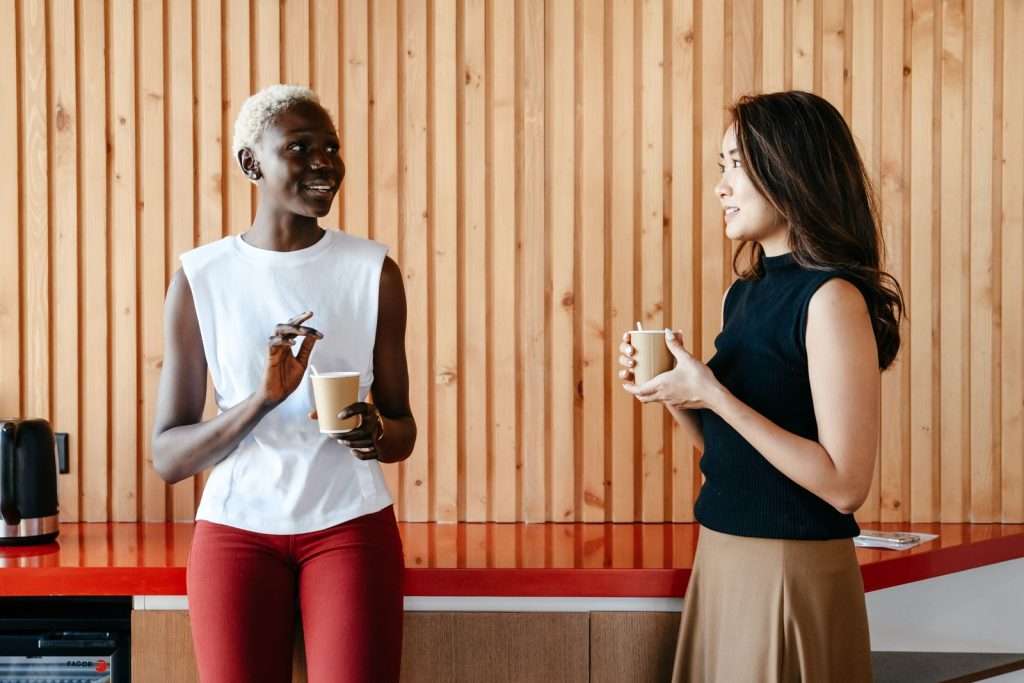Two colleagues at a small business laughing over cups of coffee